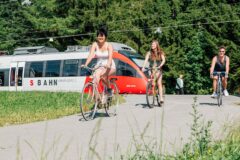 Radfahrer:innen in Feldkirch mit S-Bahn im Hintergrund